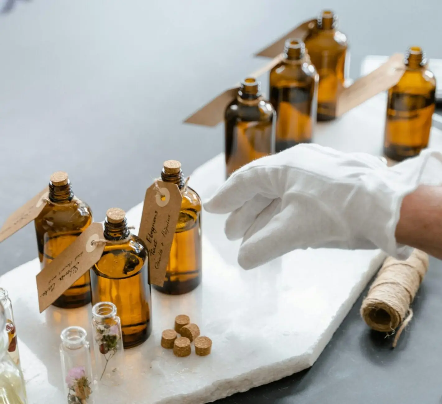 Elegant display of amber bottles and dried herbs for aromatherapy on a marble slab.